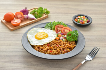 Indomie goreng Indonesian Popular Instant fried Noodle. Served with Sunny Side Egg, Tomato, Cucumber, letucce, and chilli.