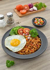 Indomie goreng Indonesian Popular Instant fried Noodle. Served with Sunny Side Egg, Tomato, Cucumber, letucce, and chilli.