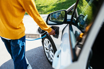 Crop man charging car near park