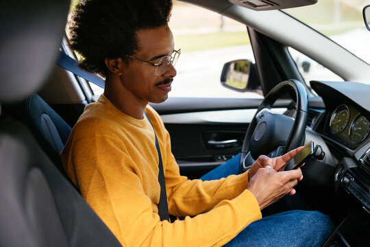 Male driver using smartphone inside car