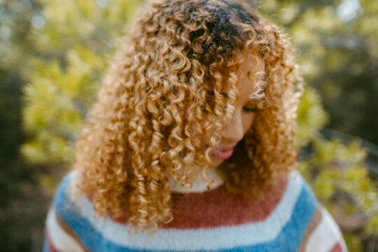 Girl with curly hair looking down outdoor in nature