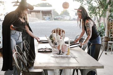 friends dressed in costume decorate outdoor table for Halloween