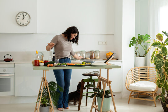 Woman with her doggy preparing lunch at kitchen