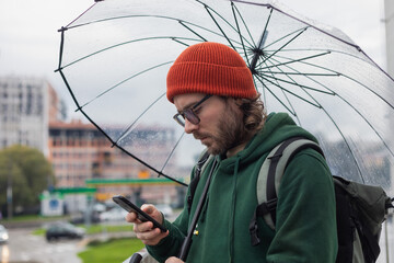 handsome man looking at phone under umbrella