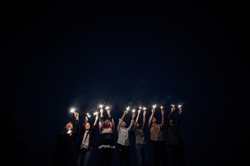 Group of young friends holding and play with fire burning sparklers