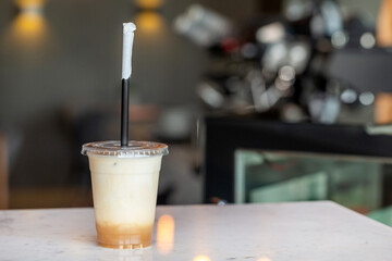 Ice latte coffee in a takeaway plastic cup at the cafe counter. Perfect summer cold beverage.