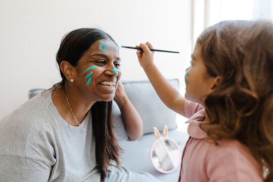Girl Paints Her Mother's Face With Blue Paint 