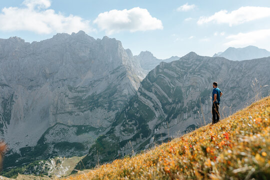 Man Standing On Slope In The Mountains.