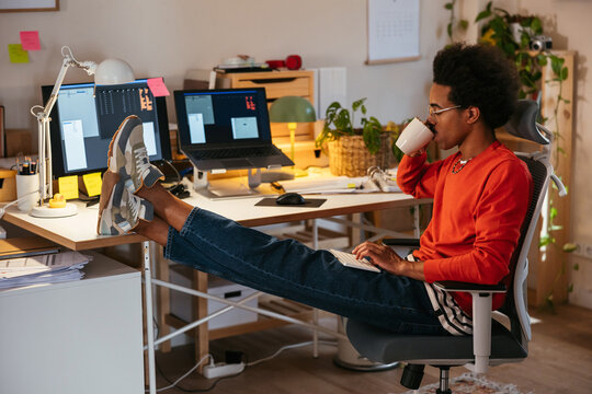 Mixed race man using computer and drinking coffee