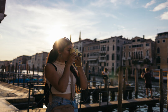 Young woman taking photos in Venice with an instant polaroid camera