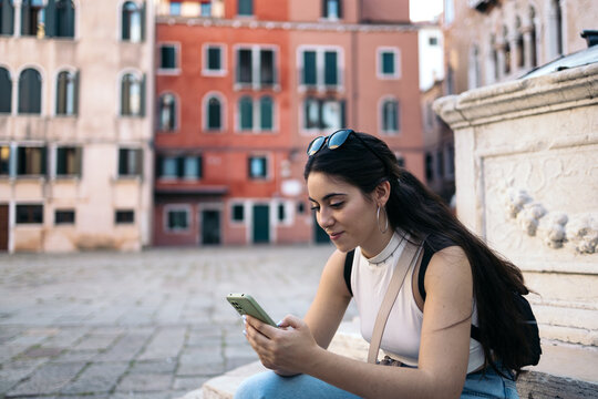 Young woman using smartphone sitting in a city square