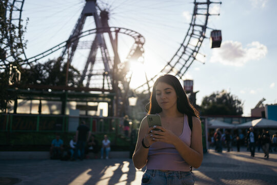 Young woman using smartphone at amusement park
