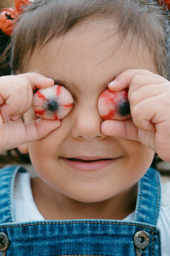 brunette girl with halloween pigtails puts jelly beans on her eyes