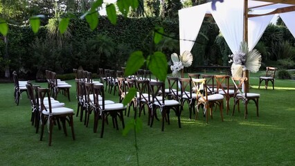 Charming event venue with rows of chairs surrounded with lush garden. Romantic marriage location along lavish green meadow. High quality FullHD footage