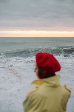 Silhouette of a woman in an autumn raincoat on the background of sea