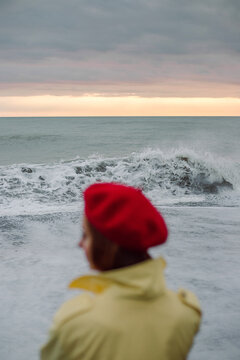 Silhouette of a woman in an autumn raincoat on the background of sea