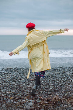 Happy woman in raincoat walking on the beach