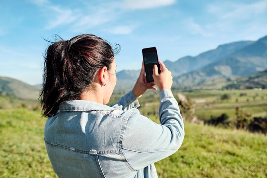 Woman taking a picture of the landscape with her phone