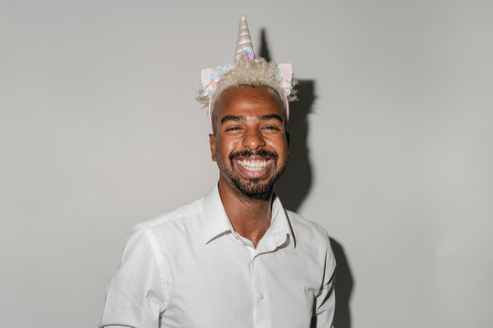 Joyful Guy With Unicorn Headband Smiling In Studio