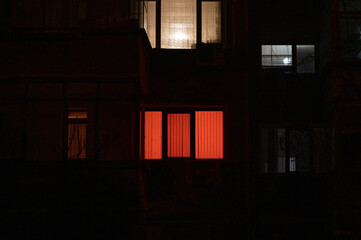 Light obscured by curtains behind a window of apartment building