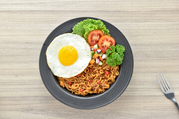 Indomie goreng Indonesian Popular Instant fried Noodle. Served with Sunny Side Egg, Tomato, Cucumber, letucce, and chilli.