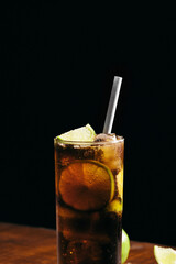 Cuba libre cocktail cold and refreshing drink for summer days on a wooden table with ice and slices of lemons