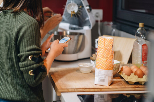 Crop mother and daughter cooking cake in kitchen