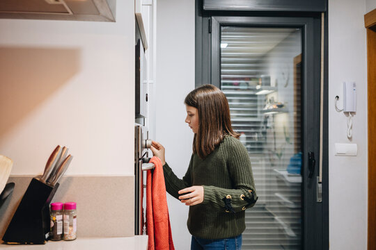 Teenage girl adjusting oven in kitchen