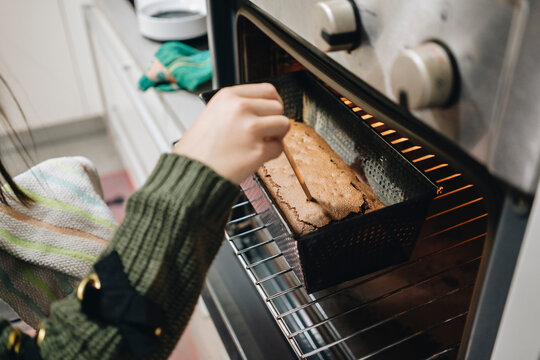 Girl checking doneness of cake baking in oven