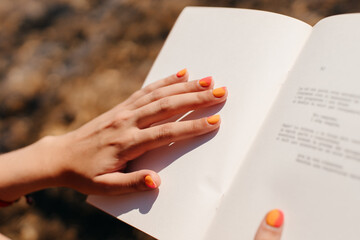 Hand with colorful nails over book