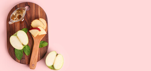 Wooden board with gravy boat of apple cider vinegar and fruits on pink background with space for text