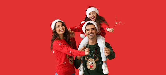 Happy family with Christmas sparklers on red background