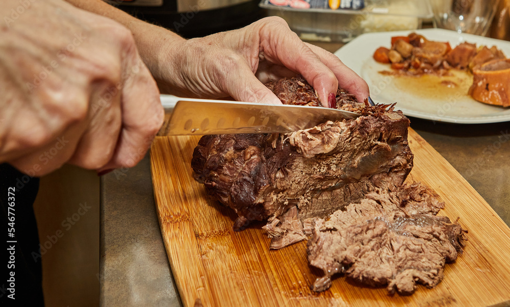 Wall mural Chef cuts slices from piece of long-cooked beef