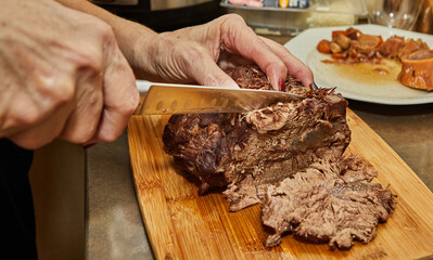 Chef cuts slices from piece of long-cooked beef