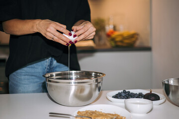 Housewife breaking an egg into a mixing bowl