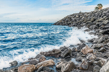 Waves crash on large cobblestones on the Playa Negro beach in Santa Cruz de Tenerife, Spain. Seascape with a stone shore of the Atlantic Ocean in the Canary Islands