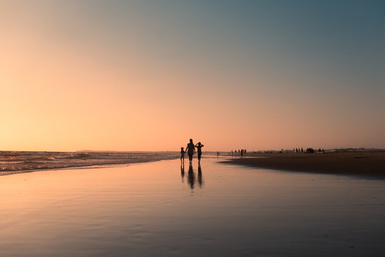 Family silhouettes enjoying beach walk at sunset