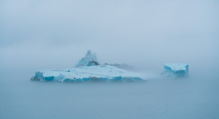 Icebergs floating in the ocean on a foggy day 