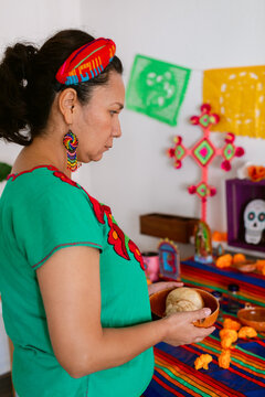 Mexican woman placing offering on altar