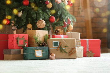 Beautiful Christmas gifts under fir tree on floor in room