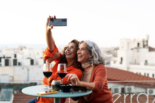 Happy senior women friends taking photo on terrace