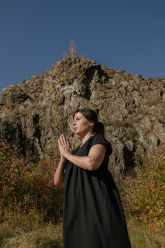 Meditative woman against the background of a stone cliff and the sky