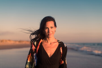 Confident woman looking at camera at beach sunset