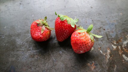 three ripe berry red strawberry on a black wooden table background. Macro. horizontal photo