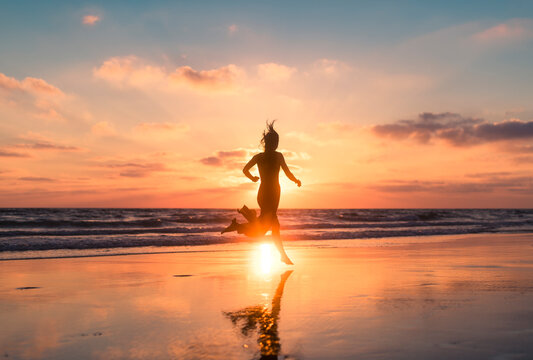 Woman silhouette running full of vitality at beach