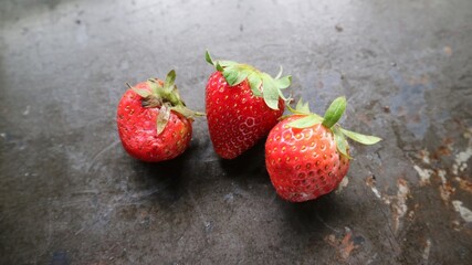 three ripe berry red strawberry on a black wooden table background. Macro. horizontal photo