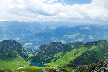 Naklejka na ściany i meble Panoramic view of lake, green alpine meadows and mountains