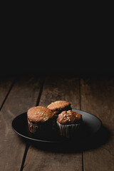 Three Cupcakes in black plate on a wooden table