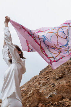 Young woman playing with her silk scarf and posing in nature