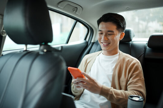 asian man using smartphone while sitting in a car